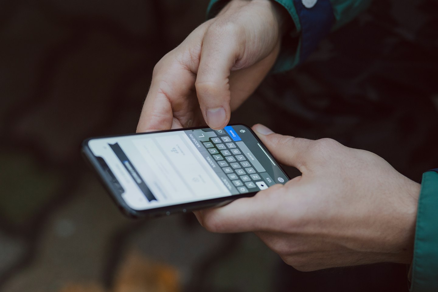 Hands typing on a smartphone with a virtual keyboard.