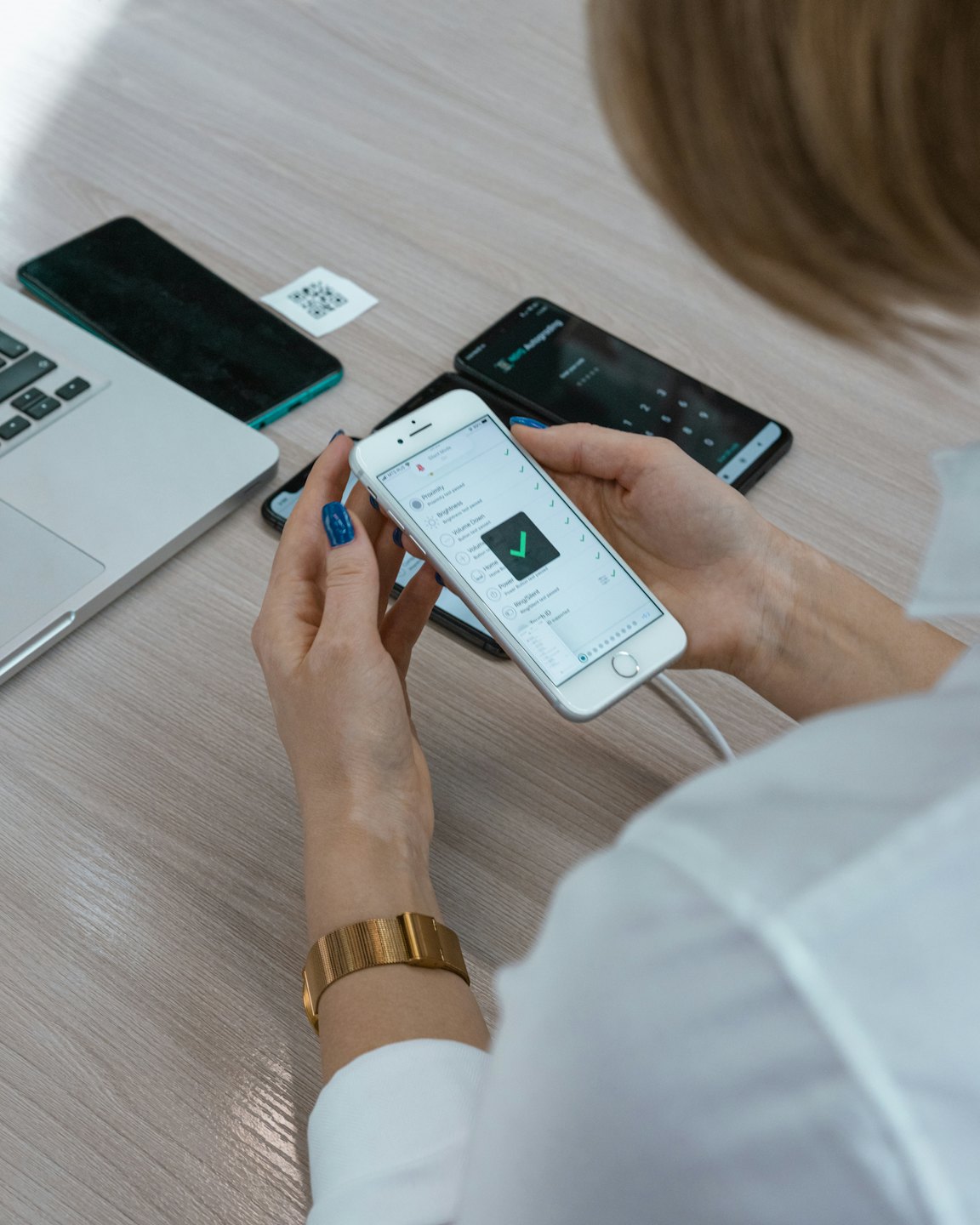 Person uses smartphone with checklist app on wooden desk.